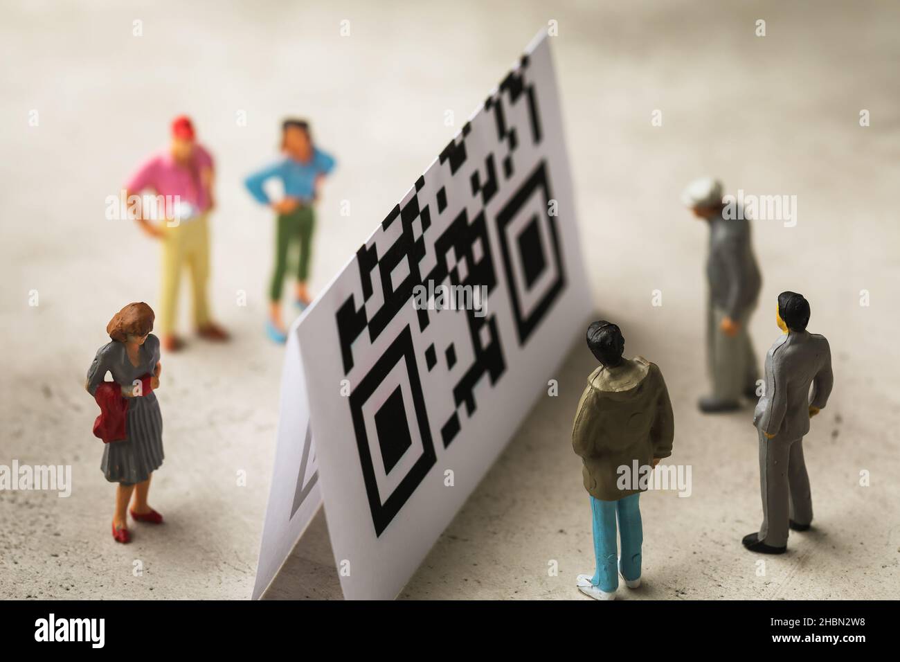 Spielzeugmänner aus Kunststoff und einem Bogen mit Barcode, dem Konzept der Spaltung der Gesellschaft mittels QR-Codes Stockfoto