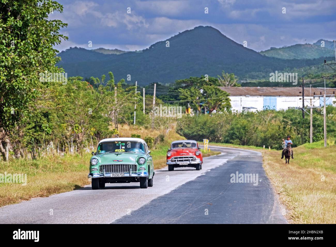 Altes Chevrolet-Taxi und rotes klassisches amerikanisches Auto fahren entlang der Circuito Sur / CS, West-Ost-Autobahn in der Provinz Cienfuegos auf der Insel Kuba Stockfoto