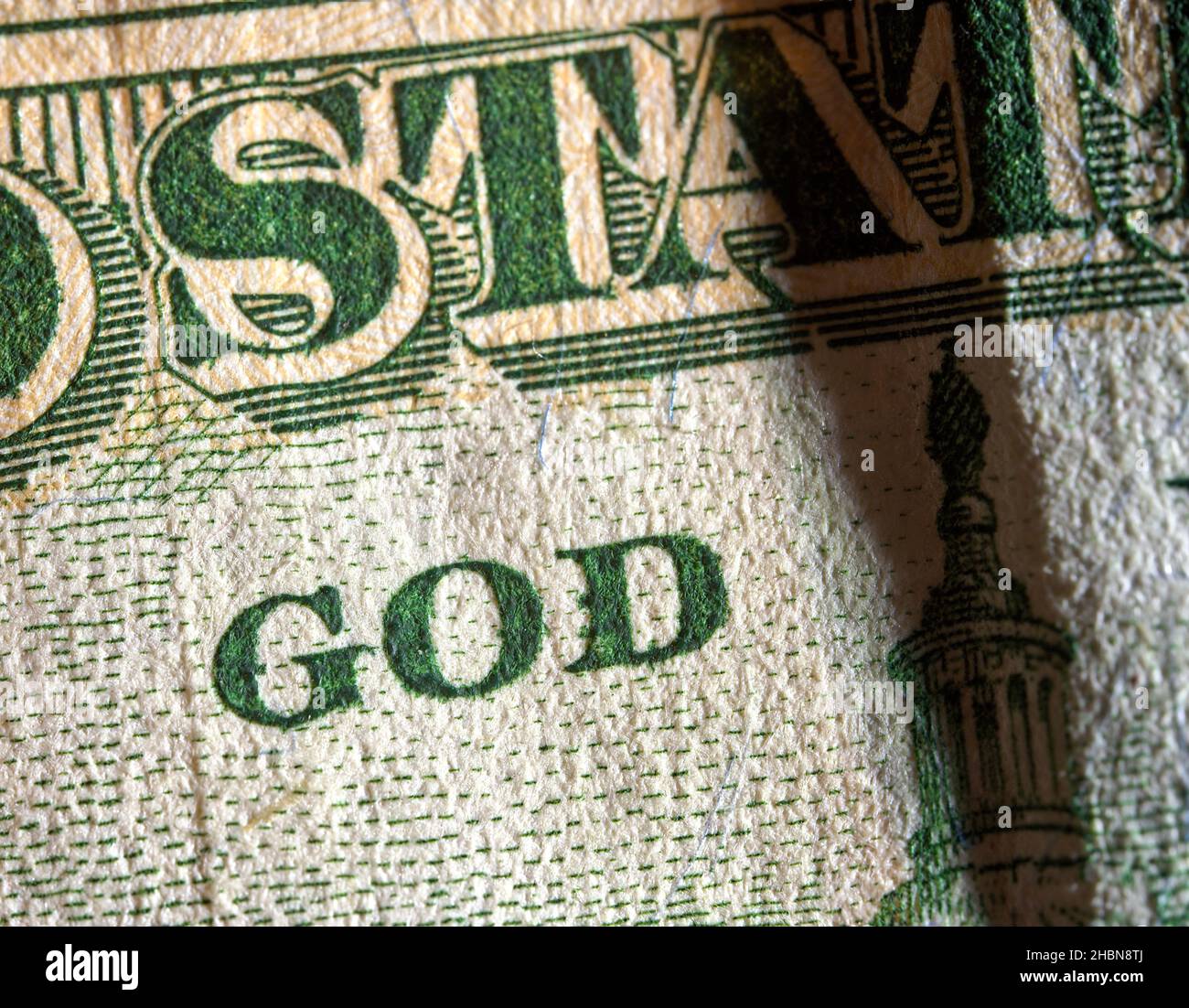 Das Wort Gott auf einer amerikanischen Banknote, über die ein Schatten fällt, Makrokonzept Stockfoto