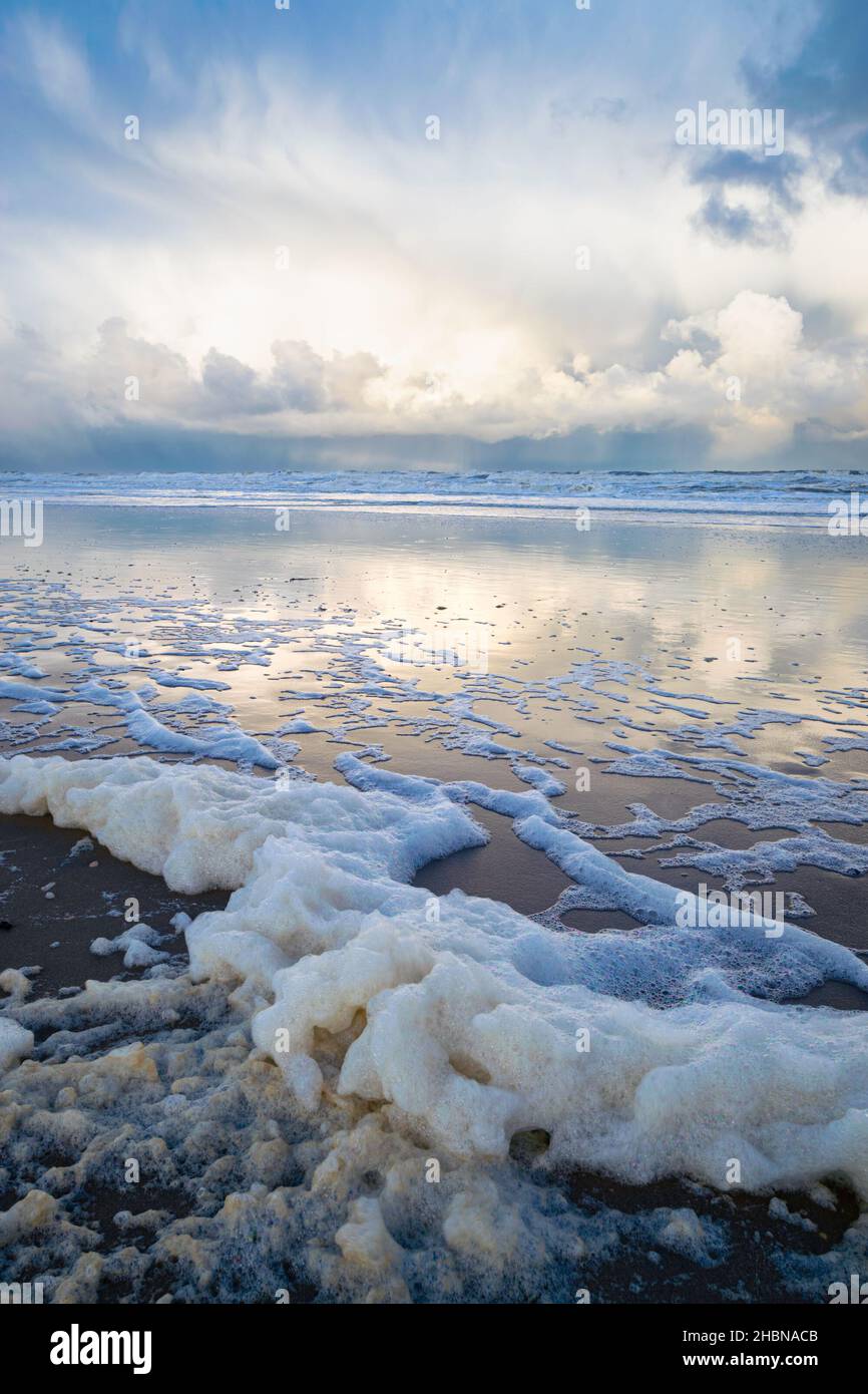 Meeresschaum am Strand nach einem Sturm. Winterliche Duschen im Hintergrund. Stockfoto