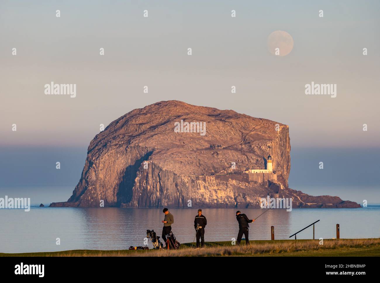 Männer, die in der Abenddämmerung auf dem Golfplatz Glen, North Berwick, vor Bass Rock, Firth of Forth, Schottland, Großbritannien, Golf spielen Stockfoto