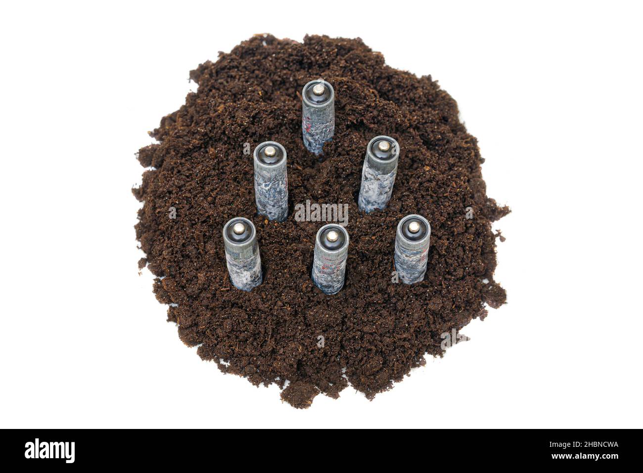 Korrodierte, gebrauchte Batterien, die auf einem Haufen Erde stehen, isoliert auf weißem Hintergrund. Verunreinigung der Natur durch unsachgemäß entsorgte Batterien. Stockfoto