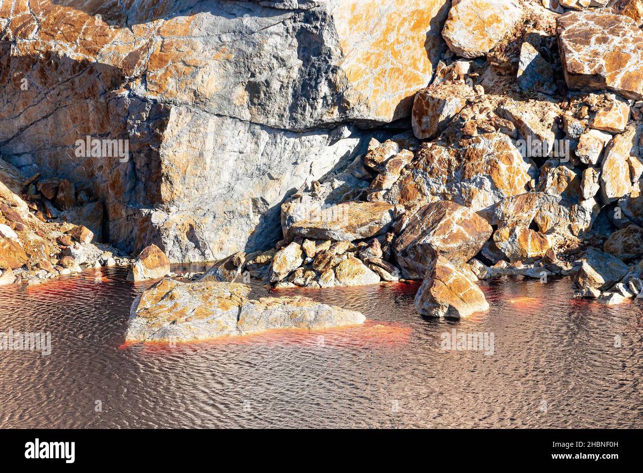 Detail der Tagebaugrube Peña del Hierro mit dem roten Wasser aufgrund der Kupfer- und Eisenkonzentration. Tiefaushub von Pyrit und Gewinnung von Mineralien Stockfoto