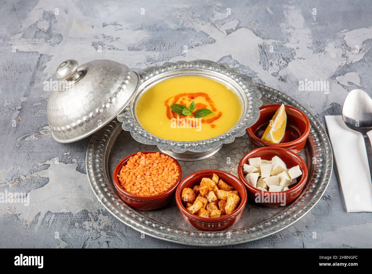 Linsensuppe in einem Kupfertablett und Kupferschüssel auf grauem Hintergrund. Stockfoto