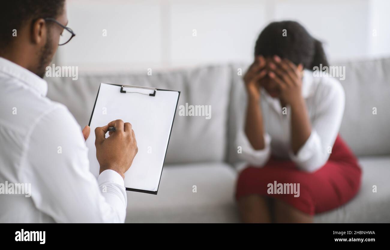 Junge schwarze Frau weint auf Rücksprache mit Psychologe, Kommunikation mit psychiatrischen Fachkraft im Büro Stockfoto