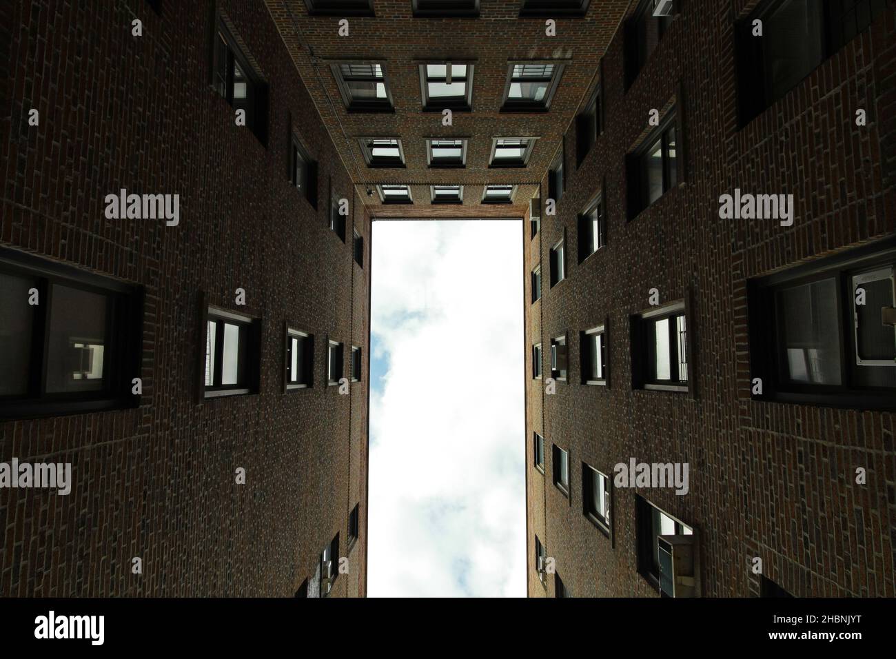 Blick nach oben auf den wolkigen Himmel durch einen Rahmen eines Wohnblocks in der Bronx, New York City Stockfoto