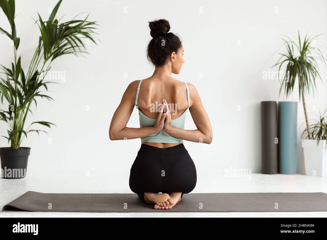 Junge Frau, Die Yoga Praktiziert, Sitzt Mit Den Händen Hinter Ihrem Rücken Zusammengeklemmt Stockfoto