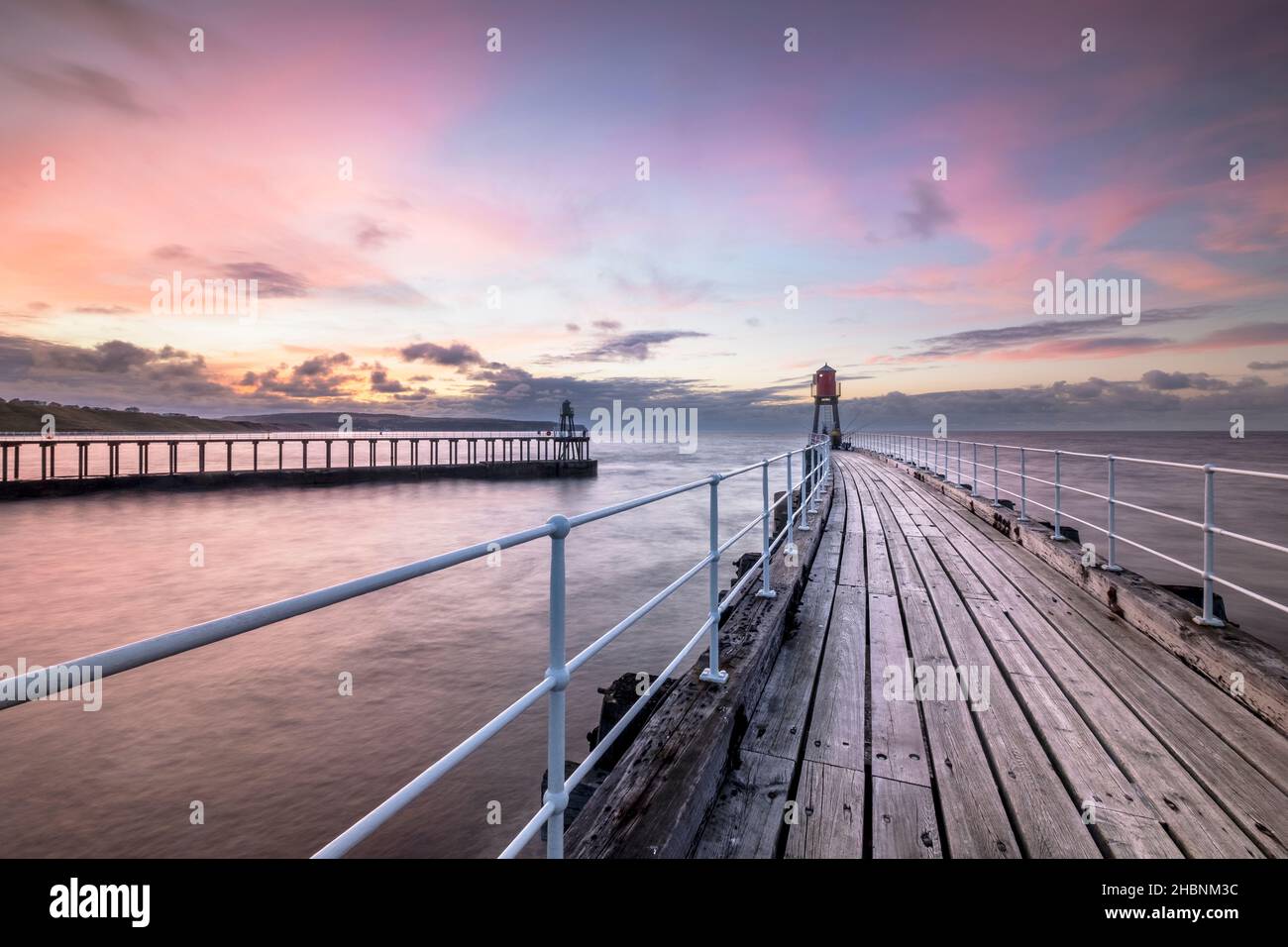 Sonnenuntergang über Whitby West Pier und Leuchtturm Stockfoto