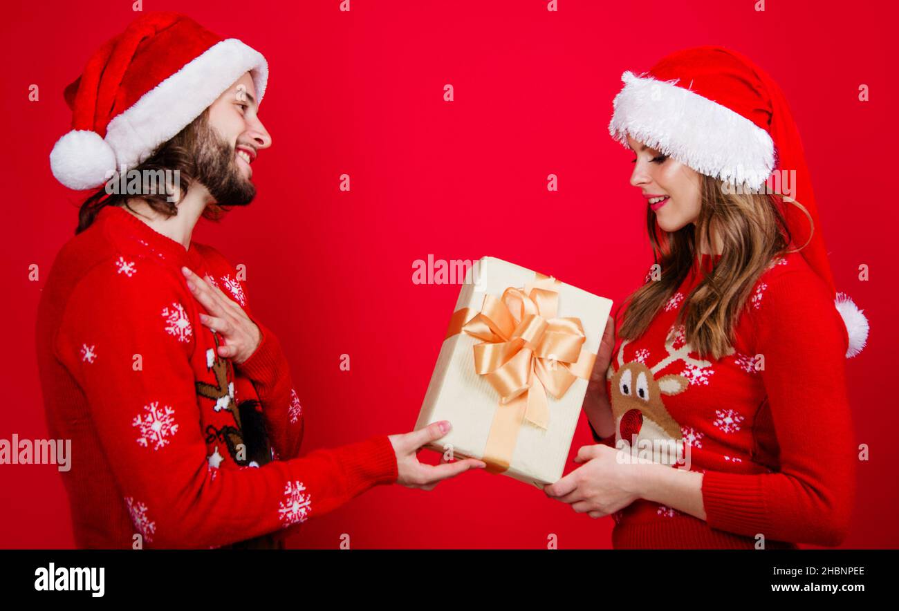Weihnachtsmann Paar in Weihnachtshut mit Geschenkbox. Freunde Mann Frau in rotem Pullover mit Neujahrsgeschenk Stockfoto