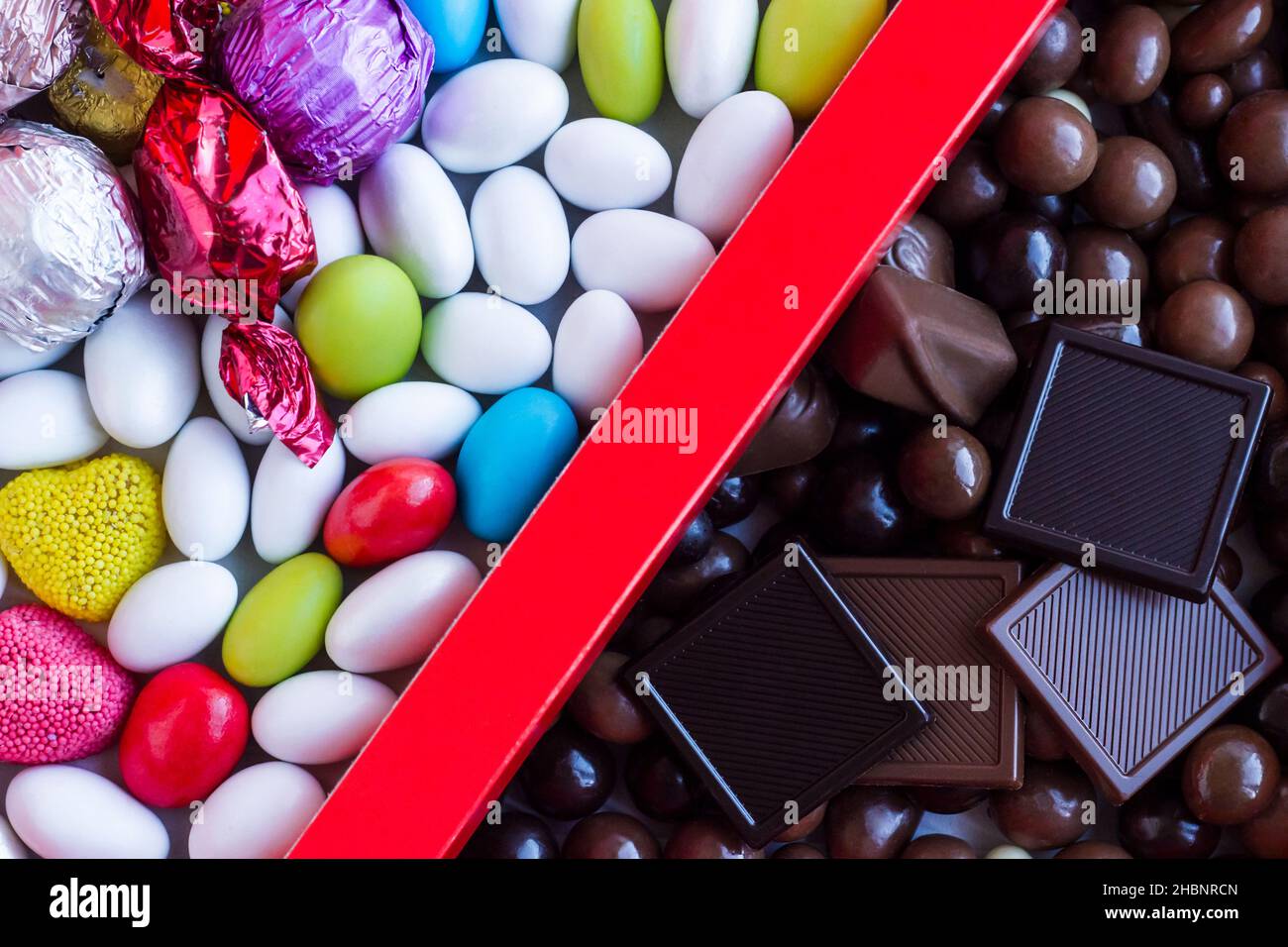 Bunte Mandel-Bonbons und Chocolate Madlen in der roten Pappschachtel.in zwei geteilt aussehend. Stockfoto