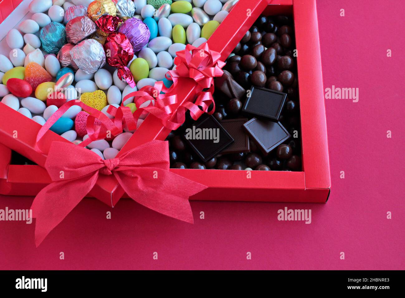 Bunte Mandel-Bonbons und Chocolate Madlen in der roten Pappschachtel.in zwei geteilt aussehend. Stockfoto