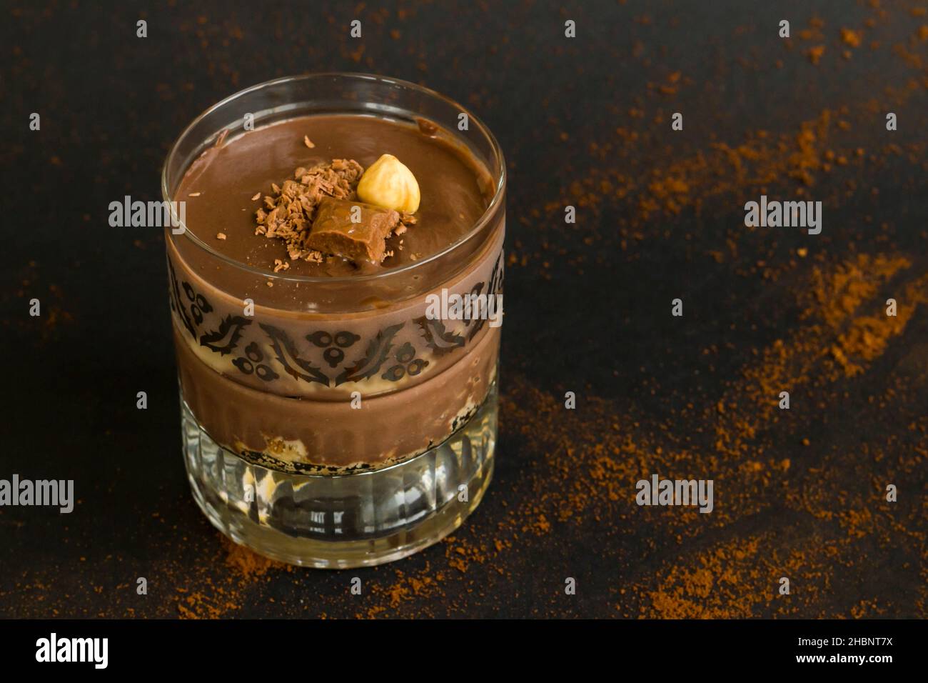 Kakaopuldding Dessert mit Keksen in Staylish Gläser auf schwarz geschichtet.garniert mit Nuss und Schokolade. Stockfoto