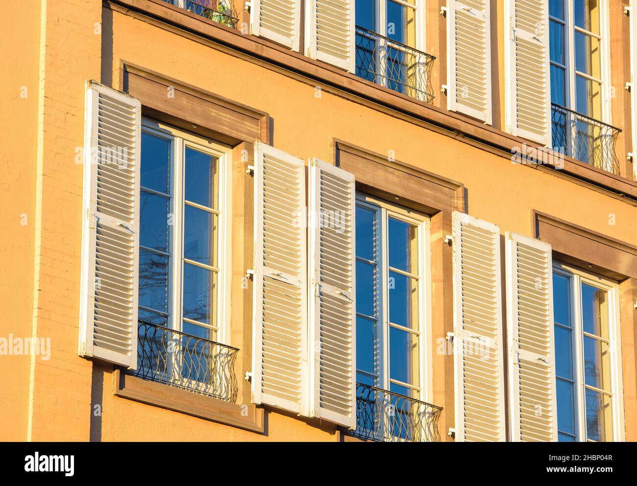 Französisches Apartmentgebäude mit blauen Fenstern, die durch UV-Dünnschicht-Blau geschützt sind Stockfoto