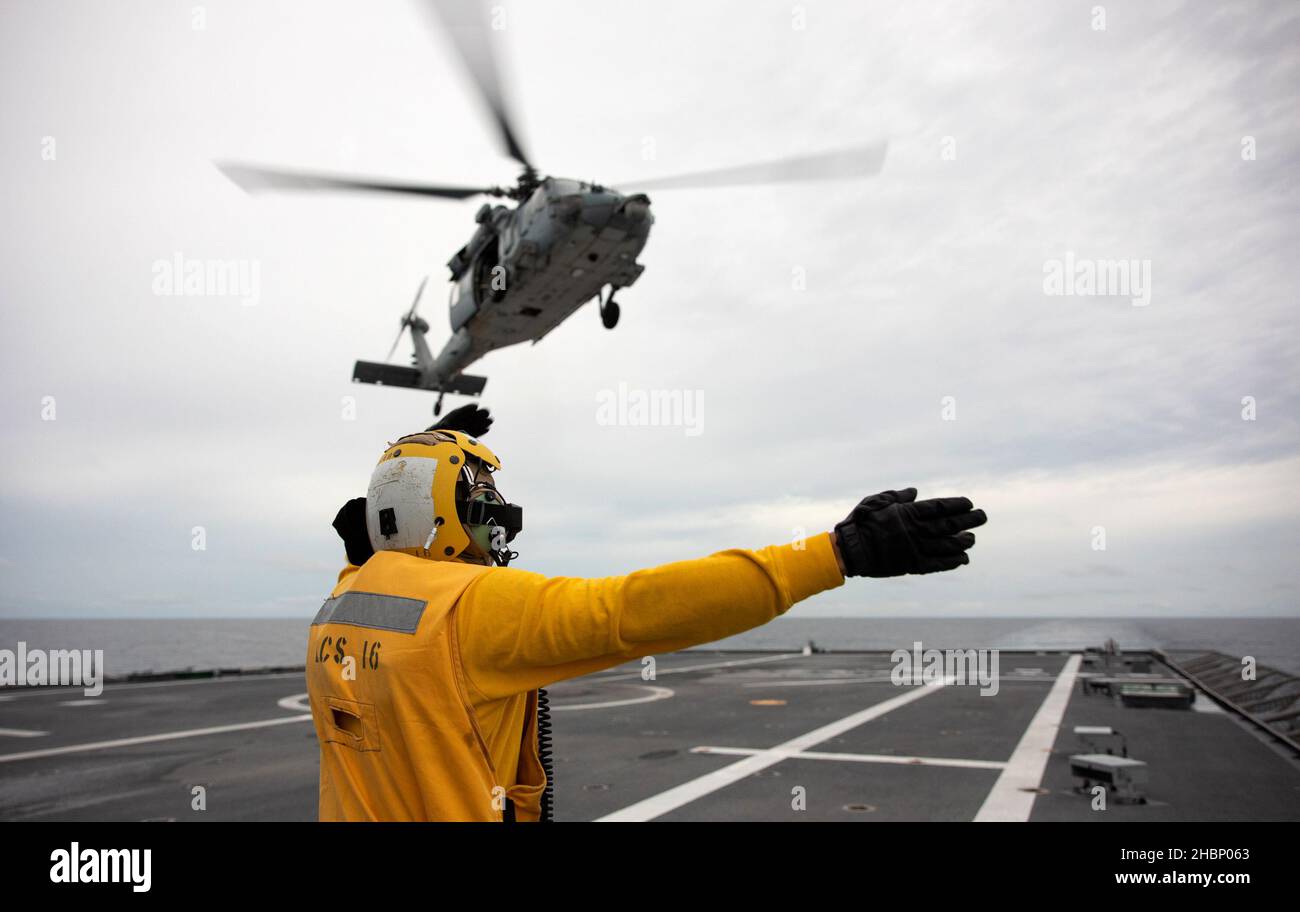 211219-N-LI768-1107 SÜDCHINESISCHES MEER (DEZ 19, 2021) – Mineman 2nd Klasse Samuel Vazquez, aus Odessa, Texas, signalisiert einen MH-60s Sea Hawk Hubschrauber, der den „Blackjacks“ des Helicopter Sea Combat Squadron (HSC) 21 zugewiesen wurde, um vom Flugdeck des Independence-Variant Littoral Combat Ship USS Tulsa (LCS 16) abzuheben. Tulsa, Teil von Destroyer Squadron (DESRON) 7, ist im Rotationseinsatz und arbeitet im US-amerikanischen Flottenbereich 7th, um die Interoperabilität mit Partnern zu verbessern und als einsatzbereite Kraft zur Unterstützung einer freien und offenen Region im Indo-Pazifik-Raum zu fungieren. (USA Navy-Foto Stockfoto