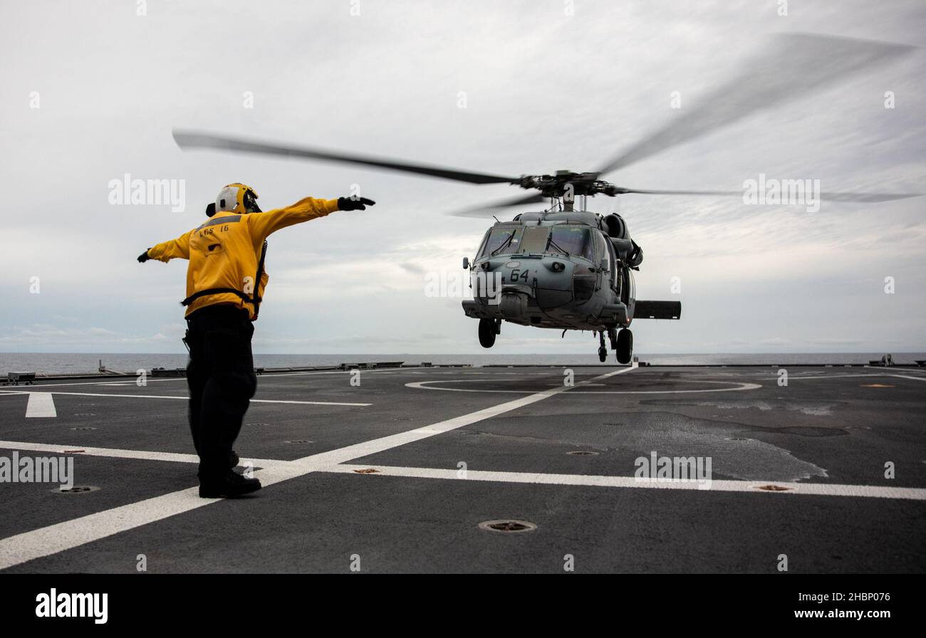 211219-N-LI768-1042 SÜDCHINESISCHES MEER (DEZ 19, 2021) – Mineman 2nd Klasse Samuel Vazquez, aus Odessa, Texas, signalisiert einen MH-60s Sea Hawk Hubschrauber, der den „Blackjacks“ des Helicopter Sea Combat Squadron (HSC) 21 zugewiesen wurde, um auf dem Flugdeck des Independence-Variant Littoral Combat Ship USS Tulsa (LCS 16) zu landen. Tulsa, Teil von Destroyer Squadron (DESRON) 7, ist im Rotationseinsatz und arbeitet im US-amerikanischen Flottenbereich 7th, um die Interoperabilität mit Partnern zu verbessern und als einsatzbereite Kraft zur Unterstützung einer freien und offenen Region im Indo-Pazifik-Raum zu fungieren. (USA Navy Foto von Ma Stockfoto
