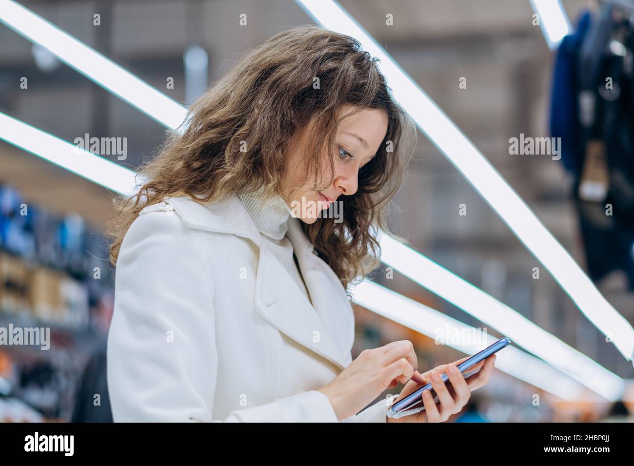 Porträt einer modernen erfolgreichen Frau wählt und kauft ein neues Telefon in einem digitalen Hypermarkt Stockfoto