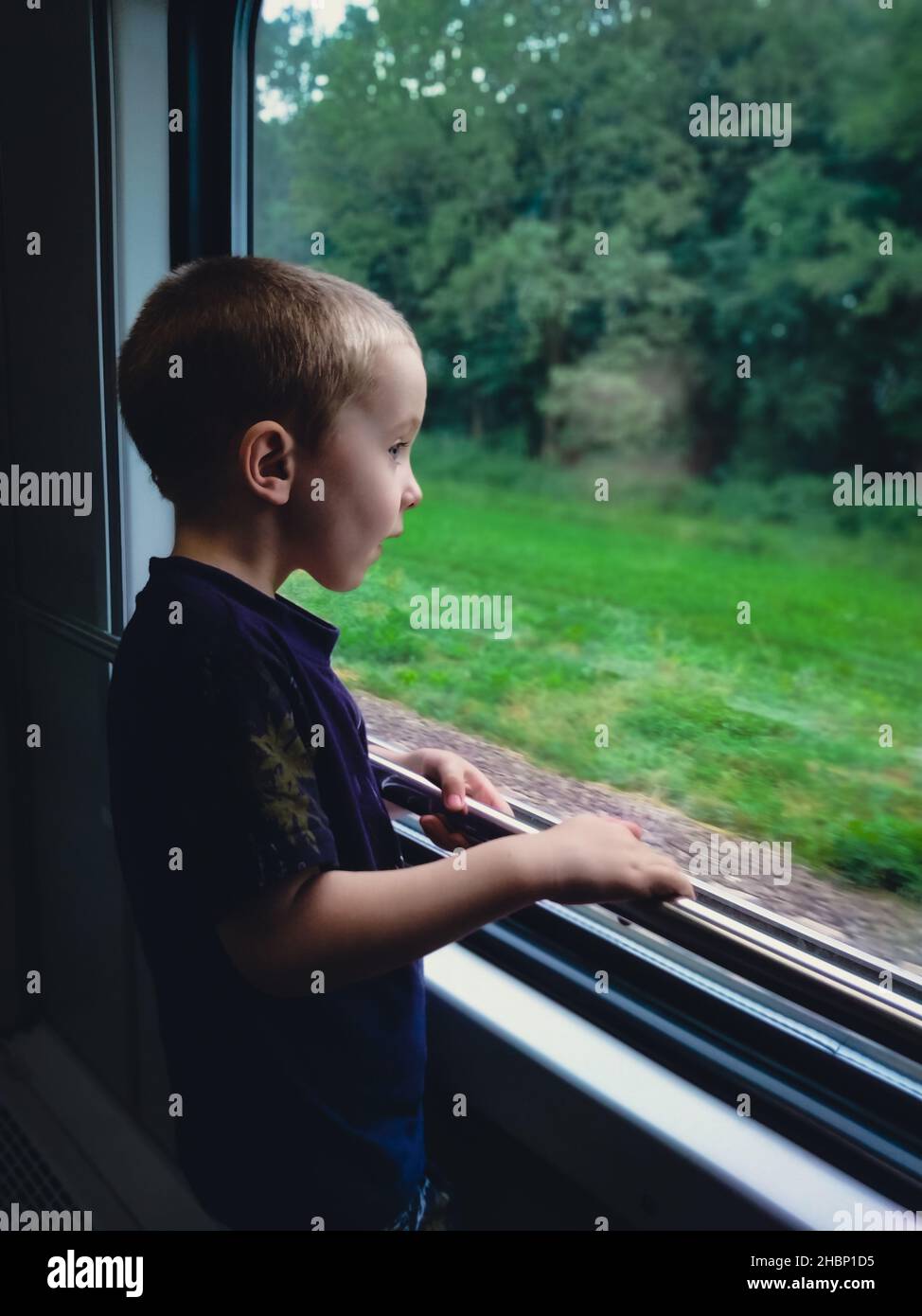 Der kleine Junge schaut durch das Fenster in einen Zug Stockfoto