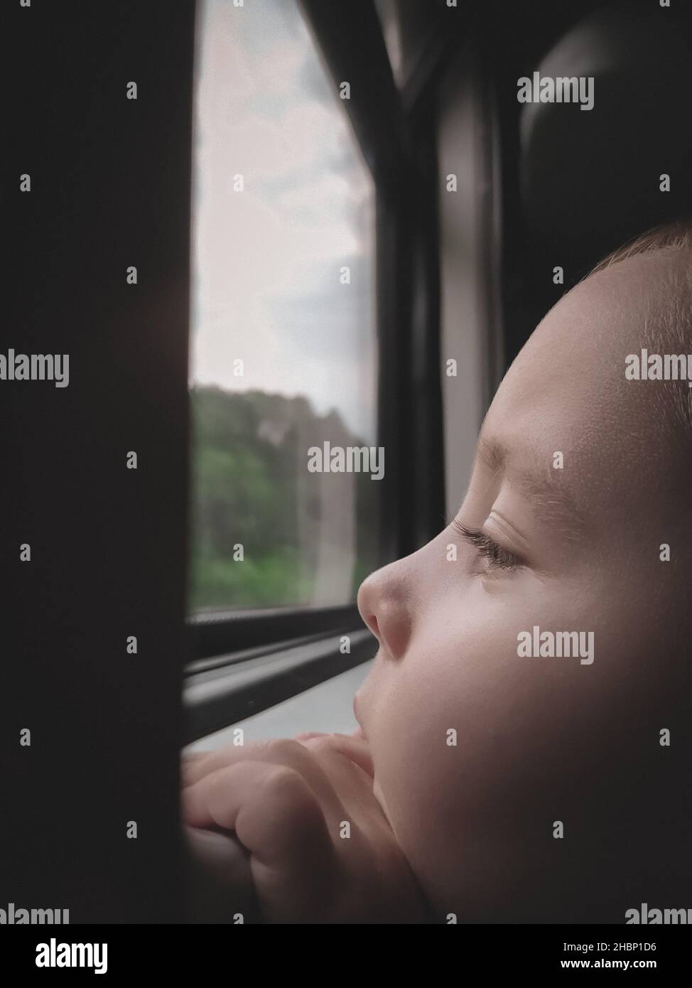 Der kleine Junge schaut durch das Fenster in einen Zug aus der Nähe Stockfoto