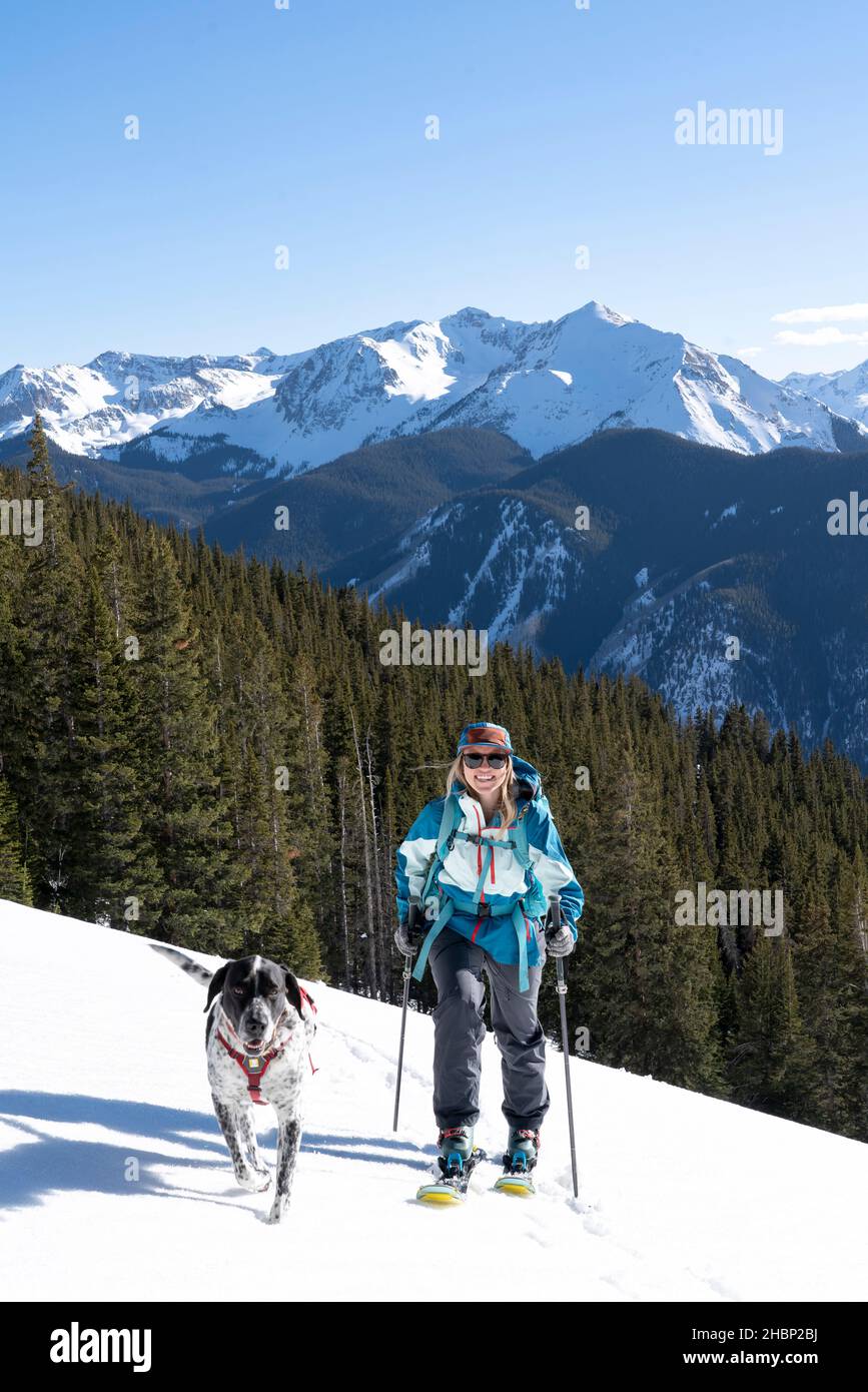 Frau mit Hund und Skistöcken Skitouren auf schneebedeckten Berg Stockfoto