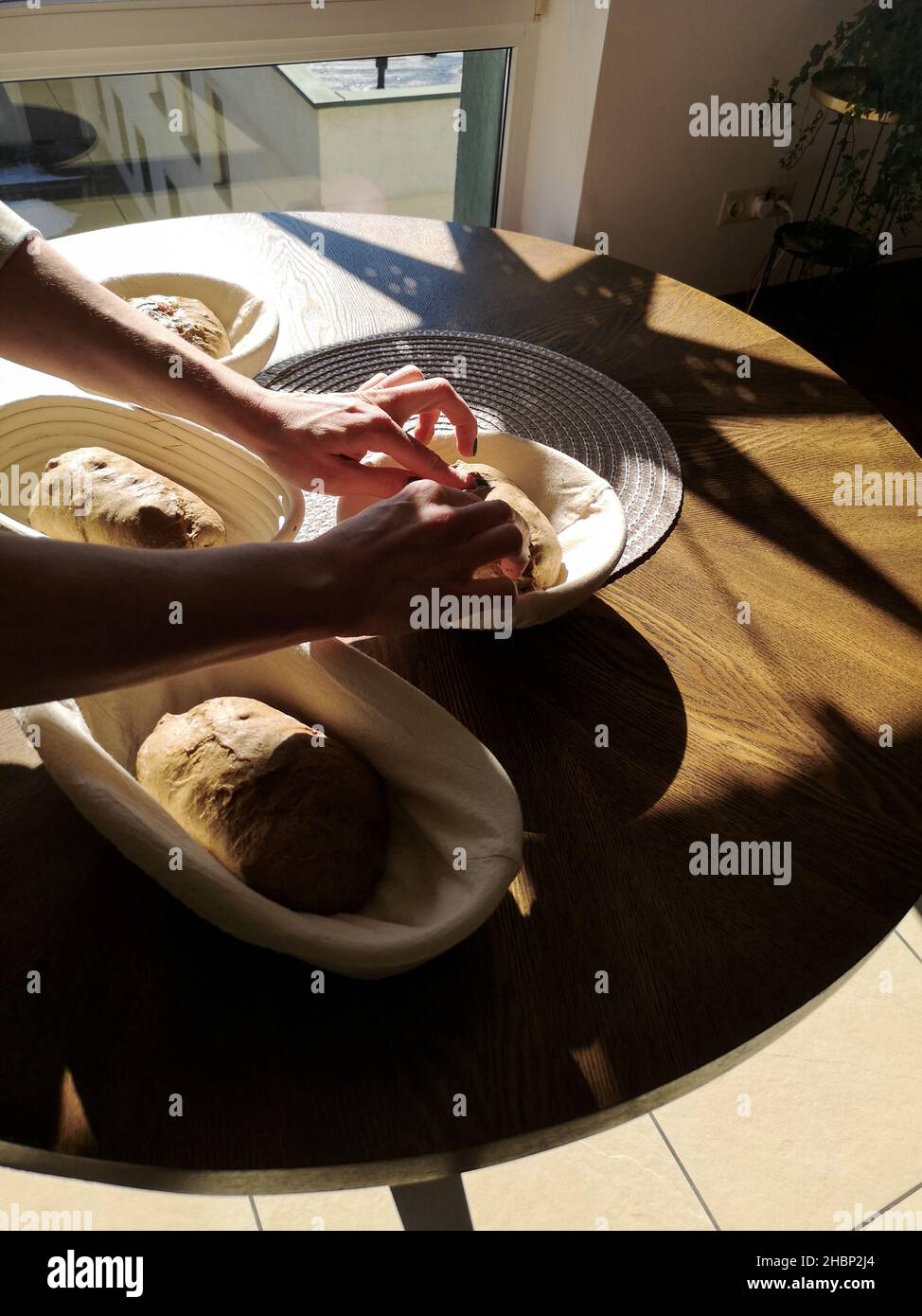 Die Hände des Bäckers legen den Teig in Körbe auf den Tisch Stockfoto