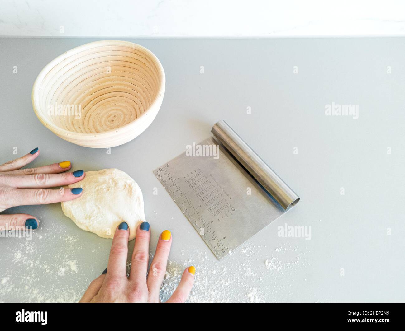 Eine Frau rollt ein Stück Teig auf den Tisch, bevor sie sich ausruht Stockfoto