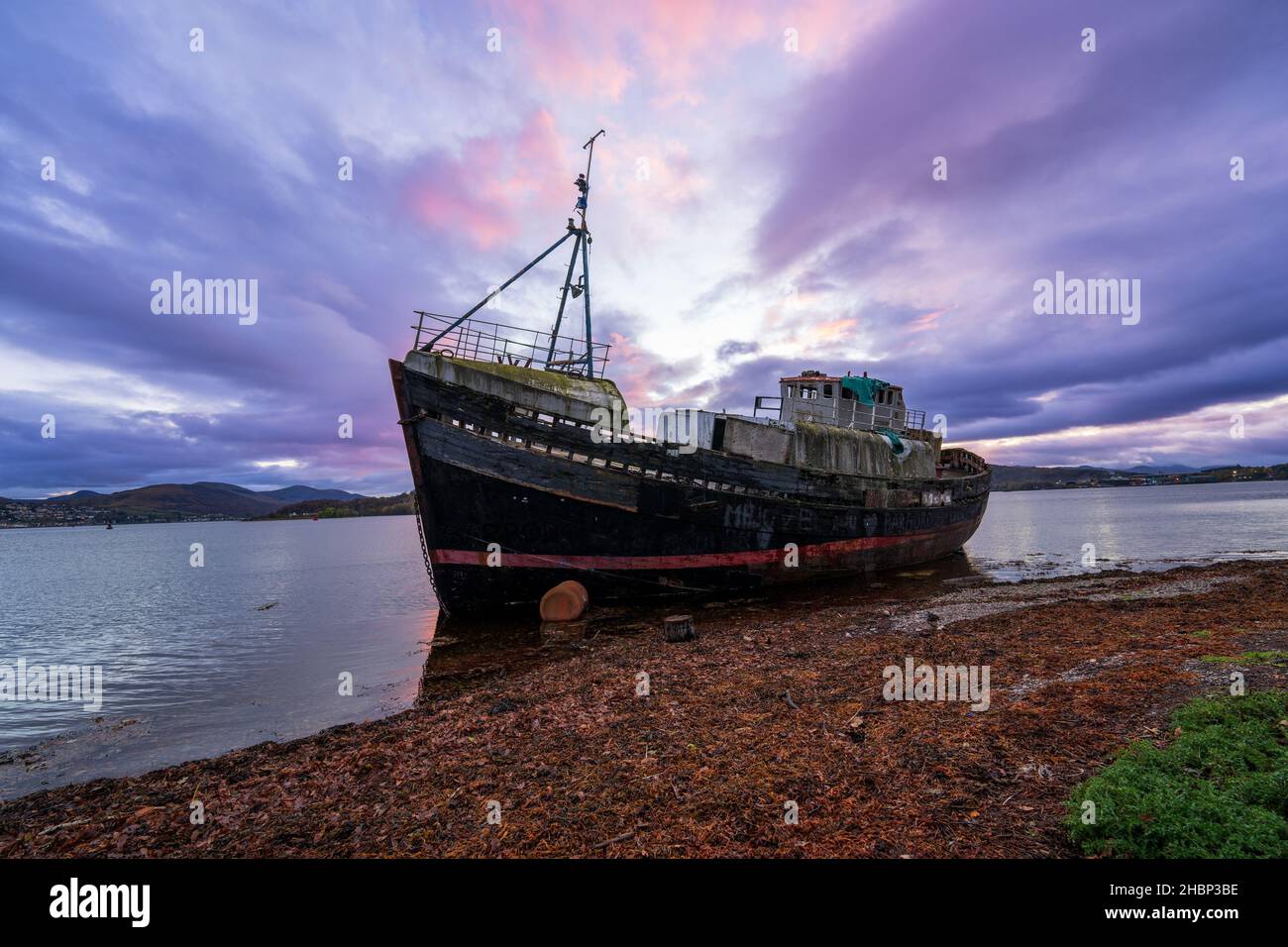 Ein geerdetes Fischerboot am Strand von Loch Linnhe, mit Ben Nevis im Hintergrund. Caol, Schottland, Großbritannien Stockfoto