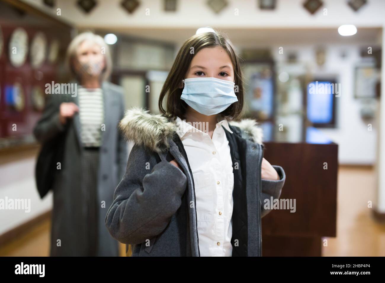 Tween Schulmädchen in medizinische Maske beobachten Kunst und Handwerk in der Galerie Stockfoto