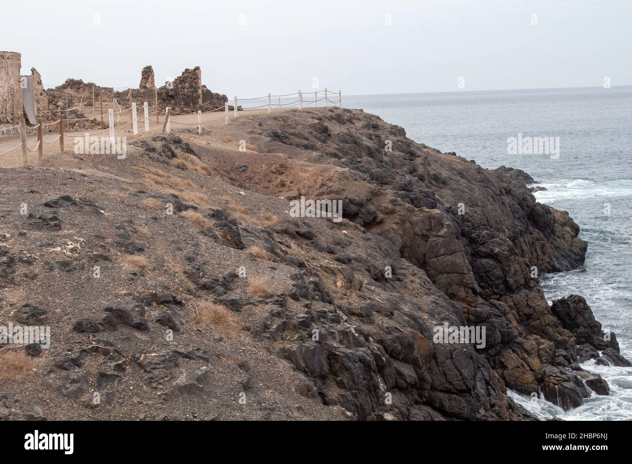 Eine kleine Insel mit alten Ruinen und einer felsigen Basis im Meer an einem sonnigen Tag Stockfoto