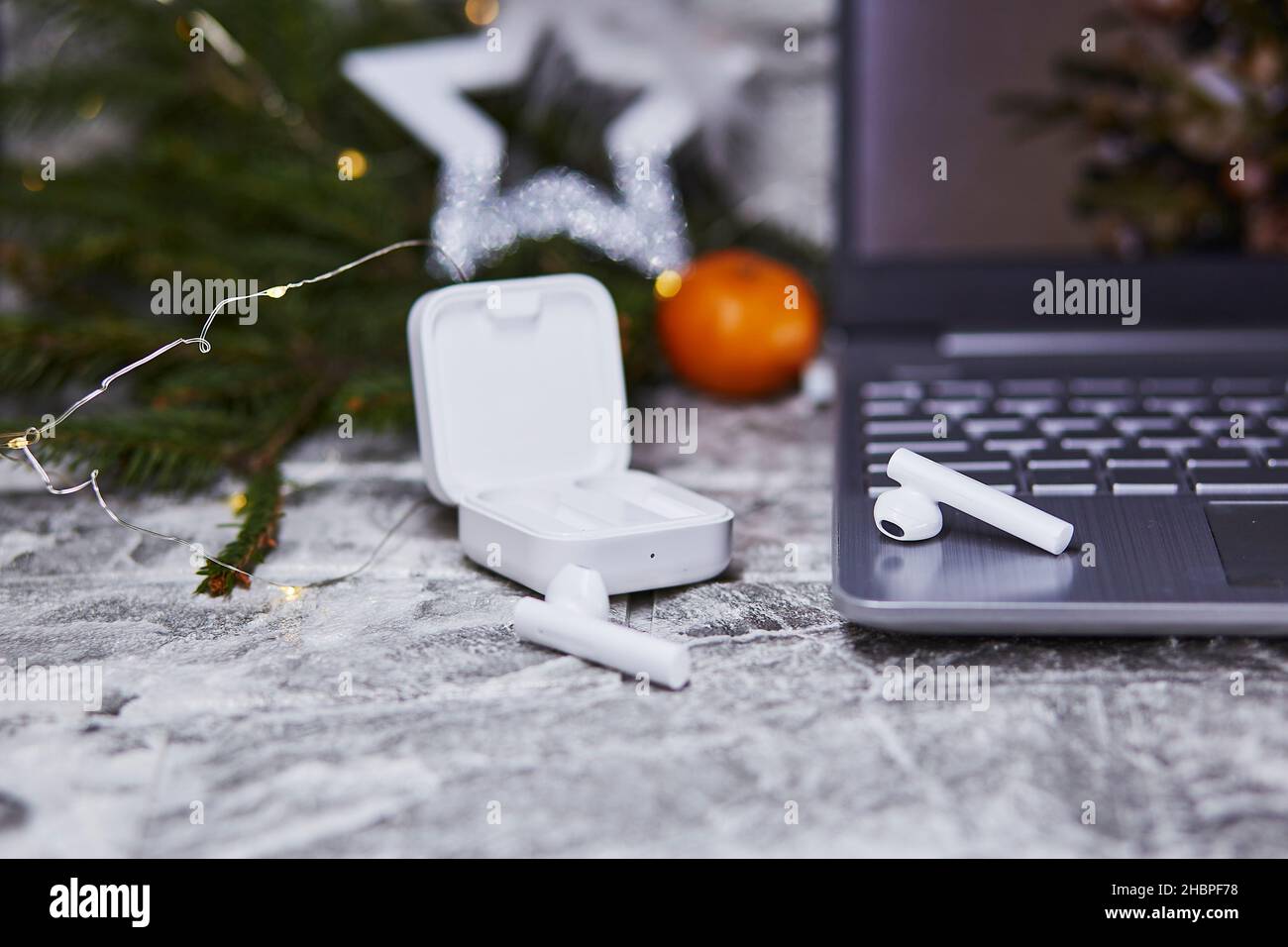 Kabellose Kopfhörer und Laptop in der Nähe von Weihnachtsdekorationen. Freiberuflich, Remote-Arbeit, Webinar-Teilnahme, Telefonieren mit Familie Konzept. Weihnachten, Neujahr vor Stockfoto