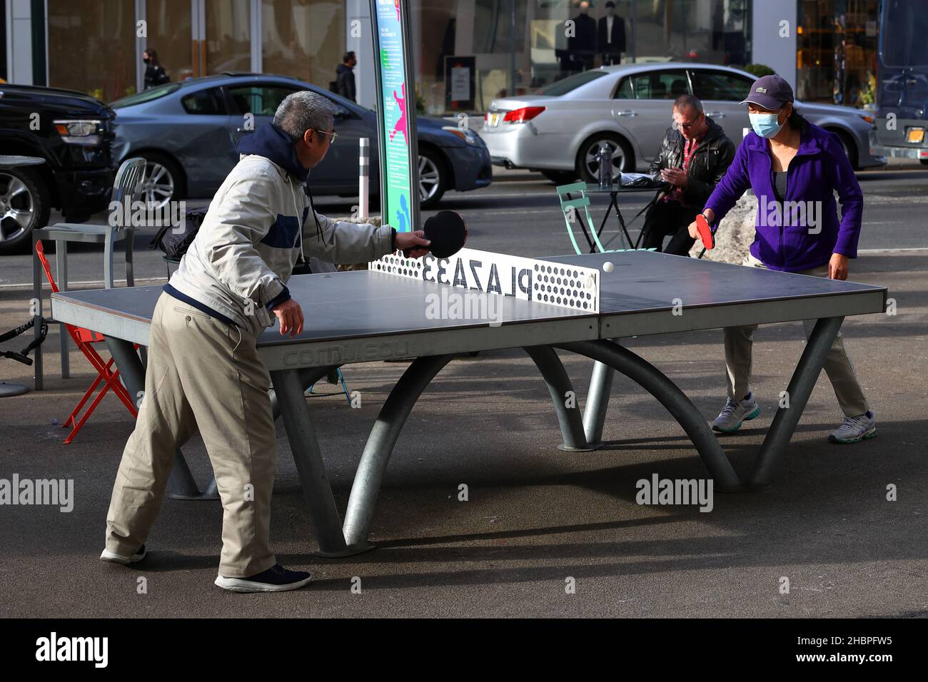 Zwei Personen asiatischer Herkunft spielen Tischtennis auf einem Cornilleau Park Outdoor-Tisch im öffentlichen Raum Plaza 33 in der Nähe des Herald Square in New York City Stockfoto