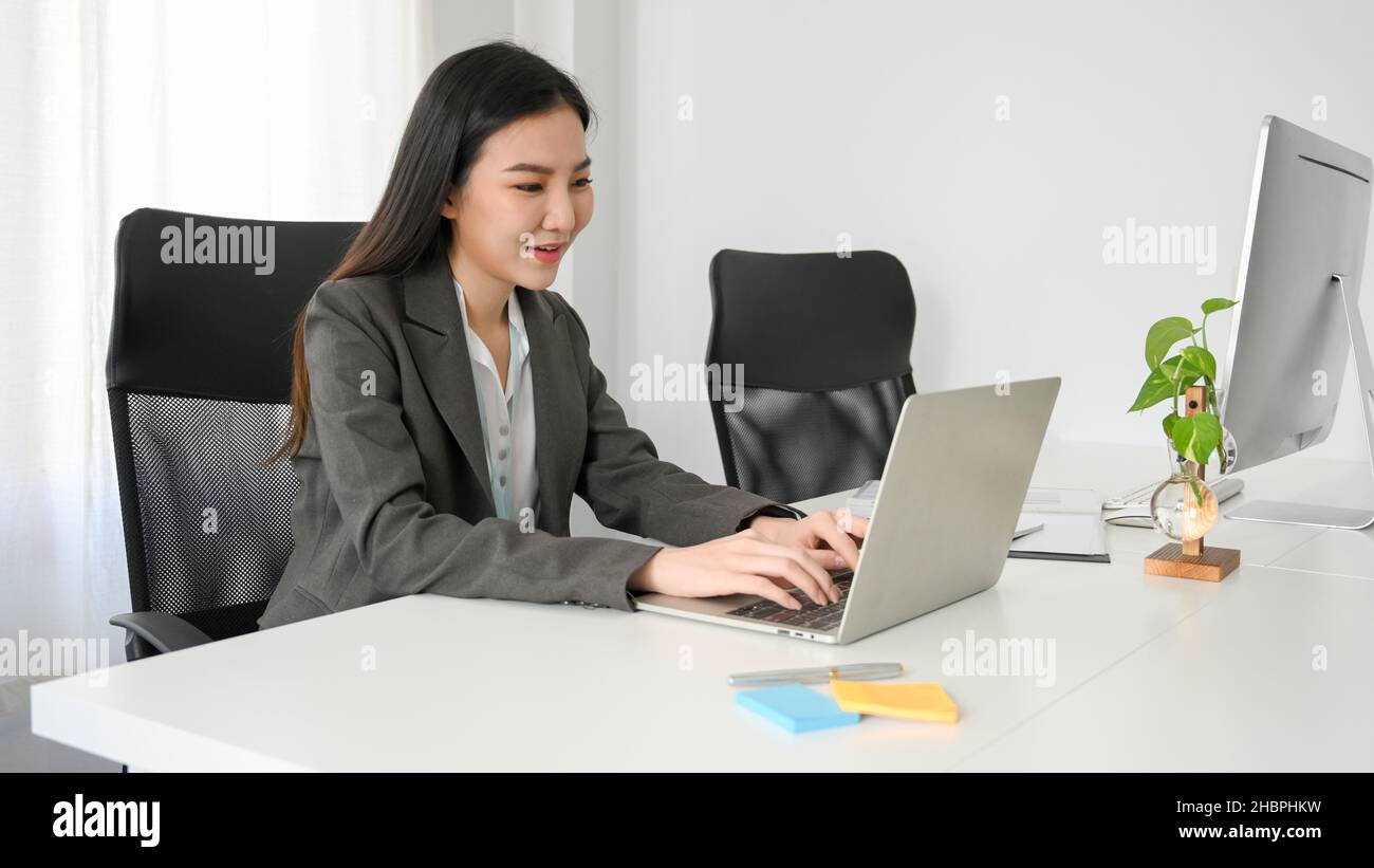 Eine professionelle Marketing-Mitarbeiterin aktualisiert die Marketingkampagne in den sozialen Medien und arbeitet an ihrem modernen Laptop am Schreibtisch. Stockfoto