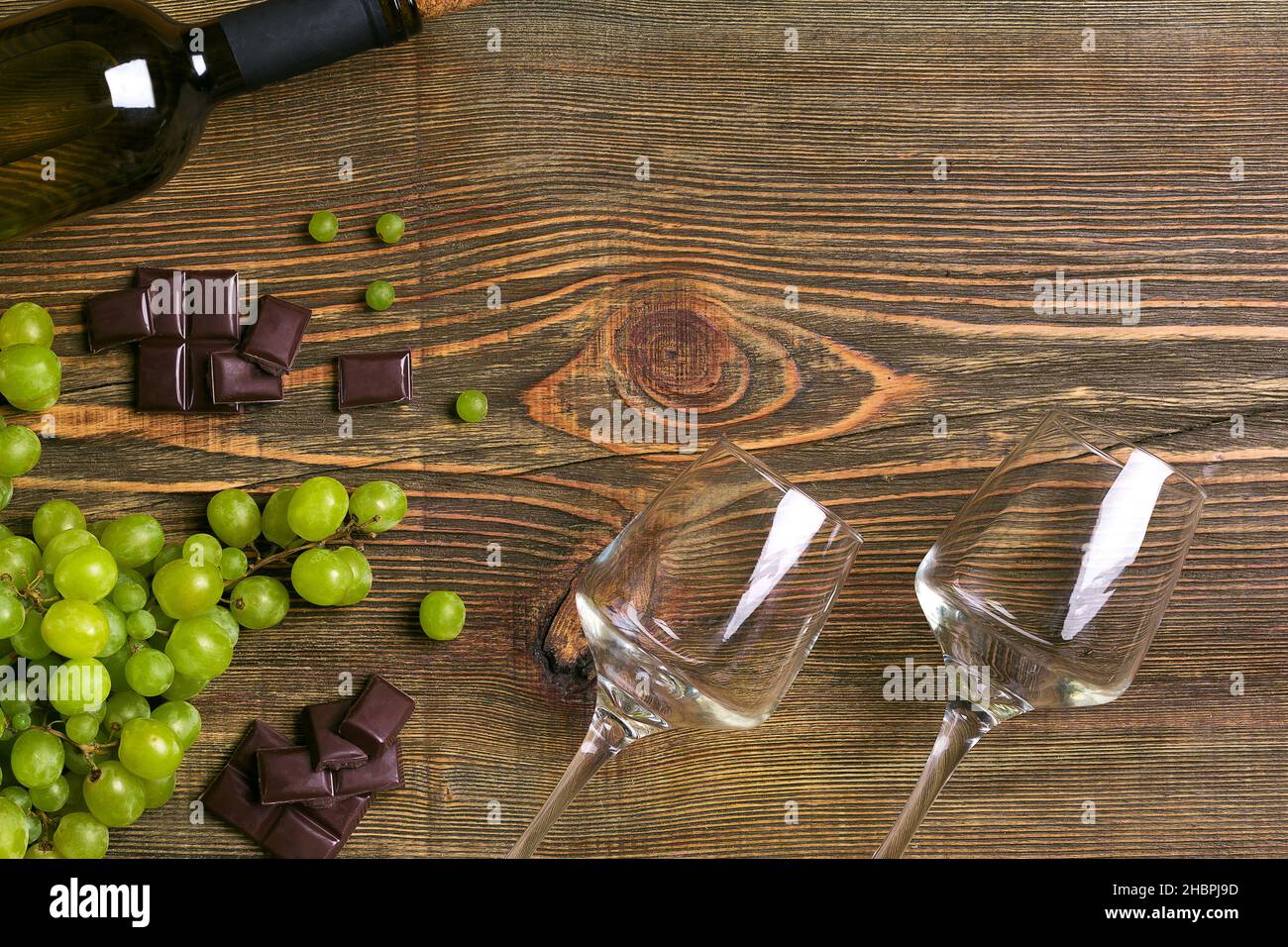 Zwei Gläser, eine Flasche Weißwein und Weintraube auf einem Holztisch Stockfoto