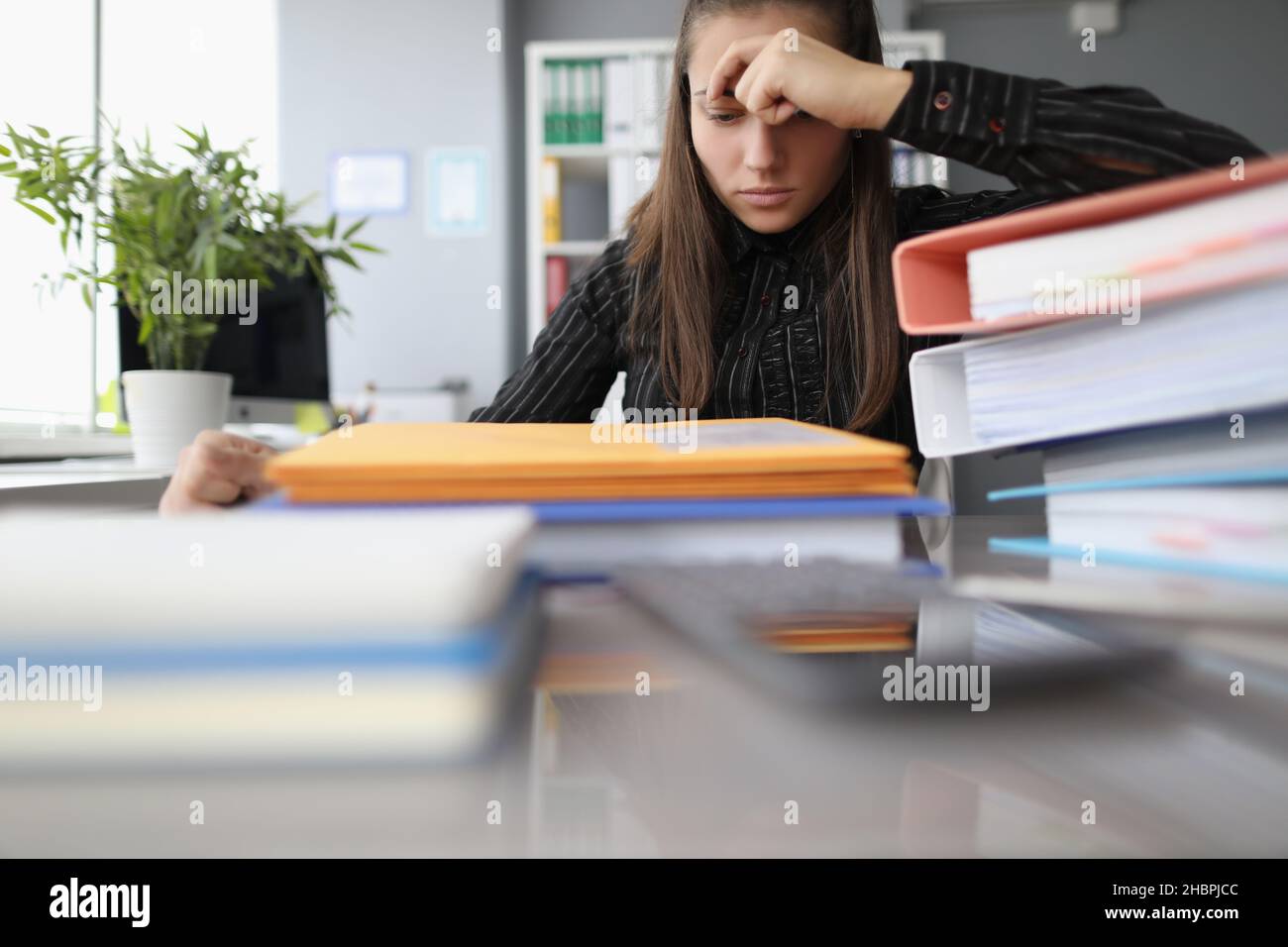 Müde überarbeiteten Frau mit hoffnungslosen Blick auf docs Haufen Stockfoto
