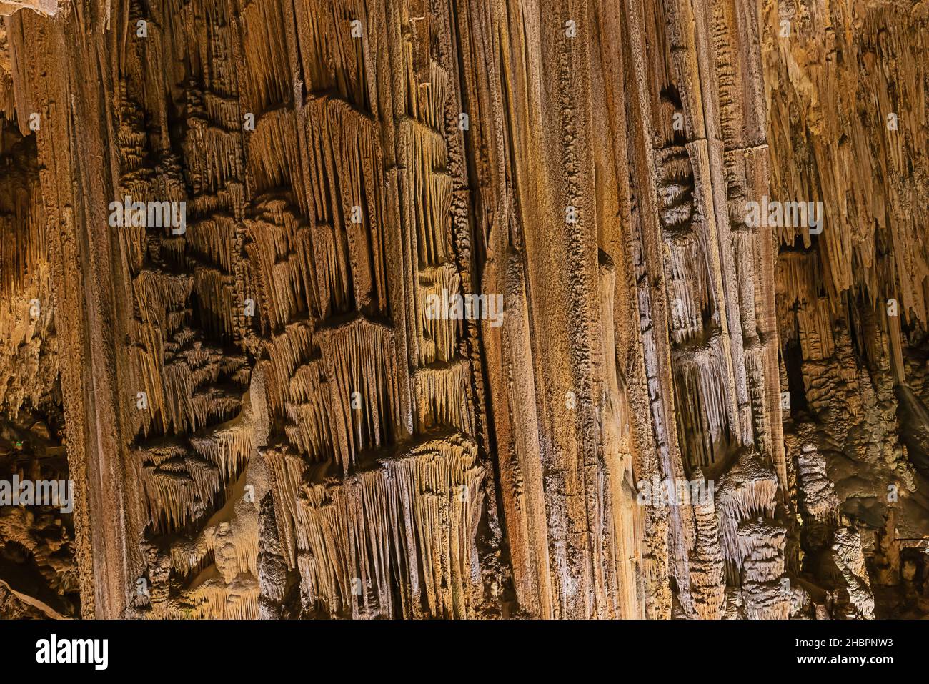 Feine, fadenartige, farbenfrohe Strukturen an einer großen Säule in der Nerja-Höhle. Selektiver Fokus auf die Spalte. Stockfoto