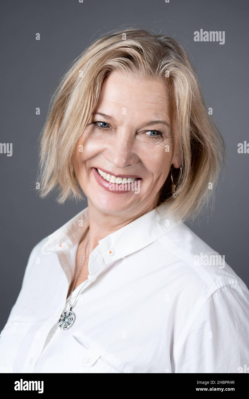 Nahaufnahme einer schönen reifen Frau mit kurzen blonden Haaren, die lächelt, während sie vor der Kamera posiert Stockfoto