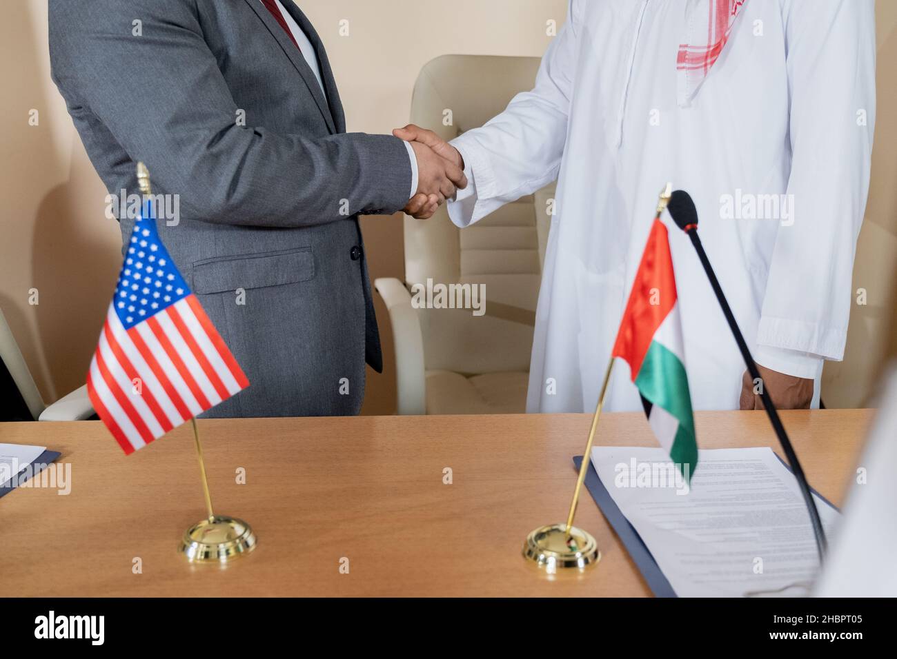 Zwei interkulturelle Politiker schütteln sich die Hände, nachdem sie eine Vereinbarung unterzeichnet und ein internationales Abkommen in formellem Umfeld getroffen haben Stockfoto
