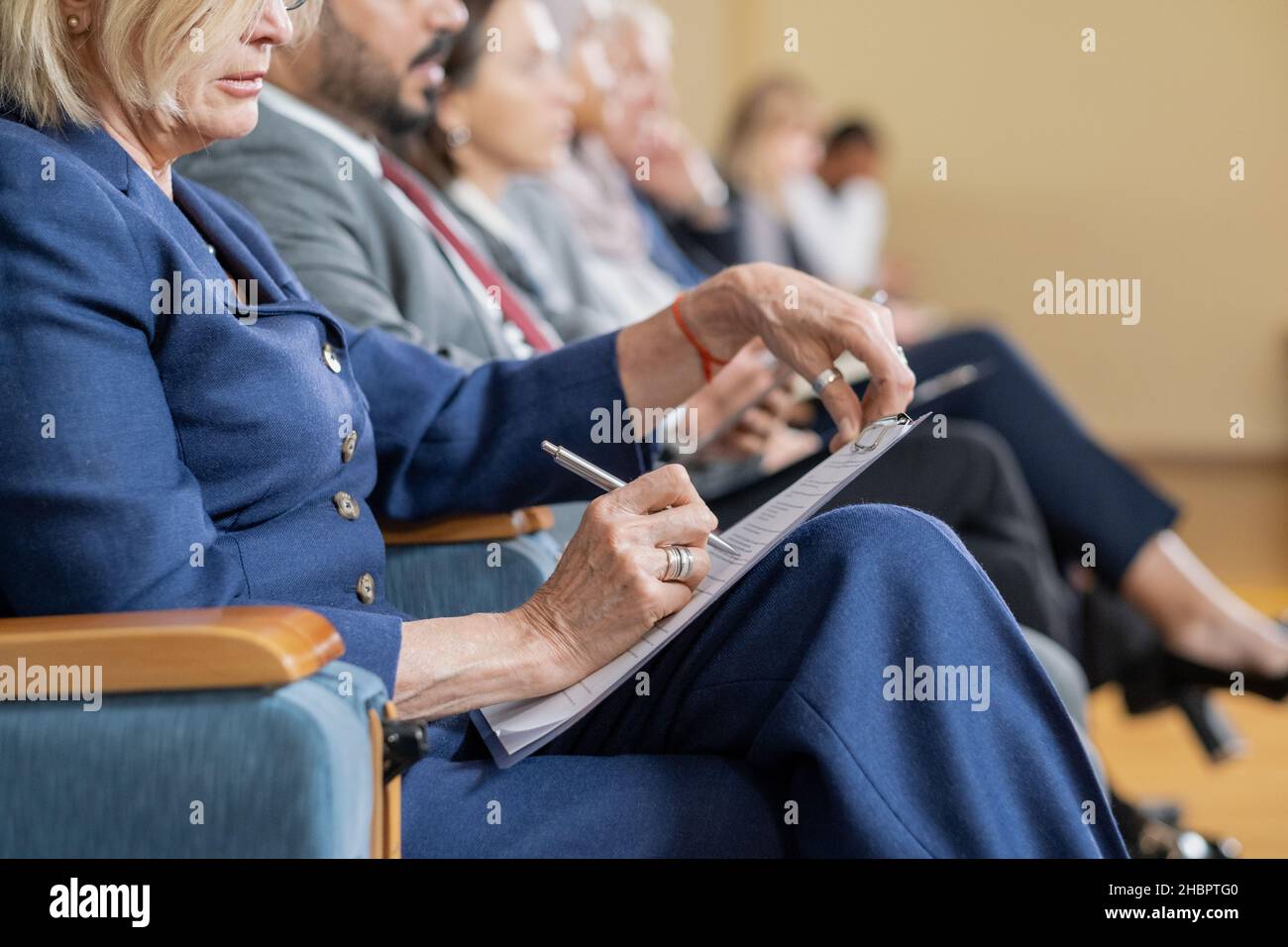 Eine Reihe von ausländischen Delegierten, die den Vortrag anhören und sich Notizen machen, während sie vor dem Redner auf der Konferenz sitzen Stockfoto