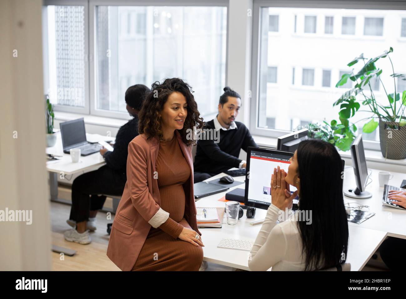 Schwanger Geschäftsfrau diskutieren mit weiblichen Kollegen im Büro Stockfoto