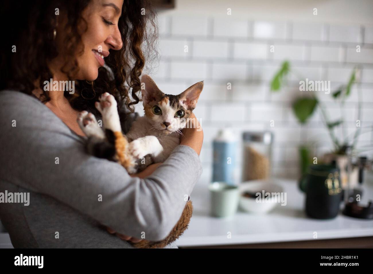 Lächelnde Frau trägt Katze zu Hause Stockfoto