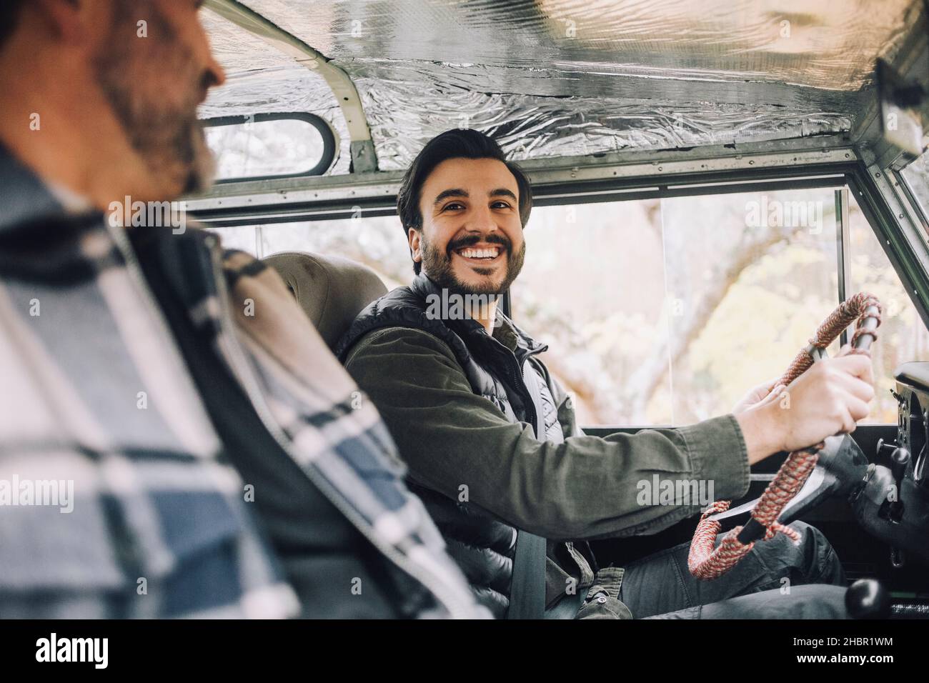 Glücklicher Sohn im Gespräch mit dem Vater, während er in einem Sportfahrzeug sitzt Stockfoto