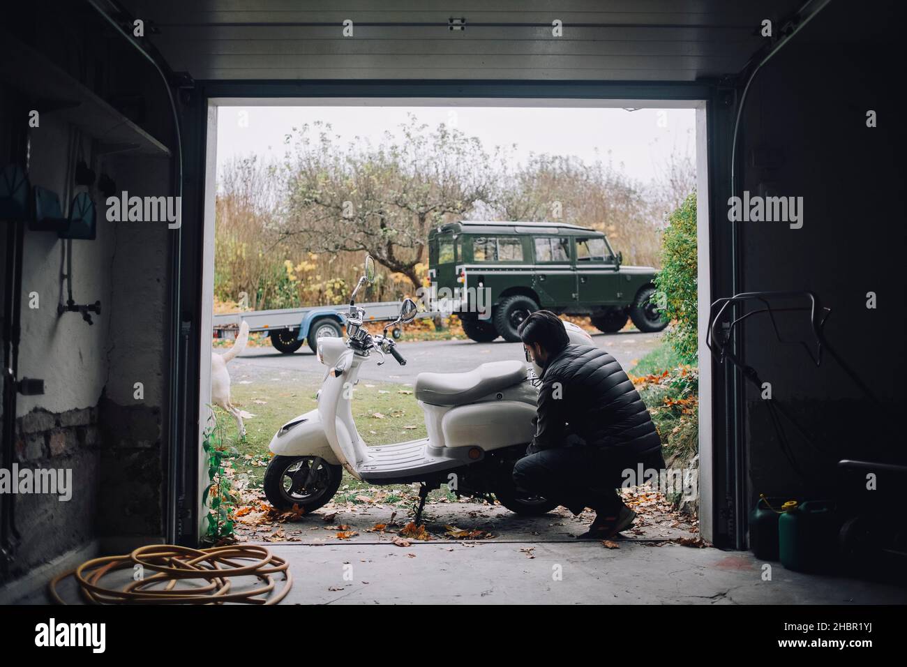 Mittlerer Erwachsener Mann repariert Motorroller in der Garage Stockfoto Mittlerer Erwachsener Mann repariert Motorroller in der Garage Stockfoto