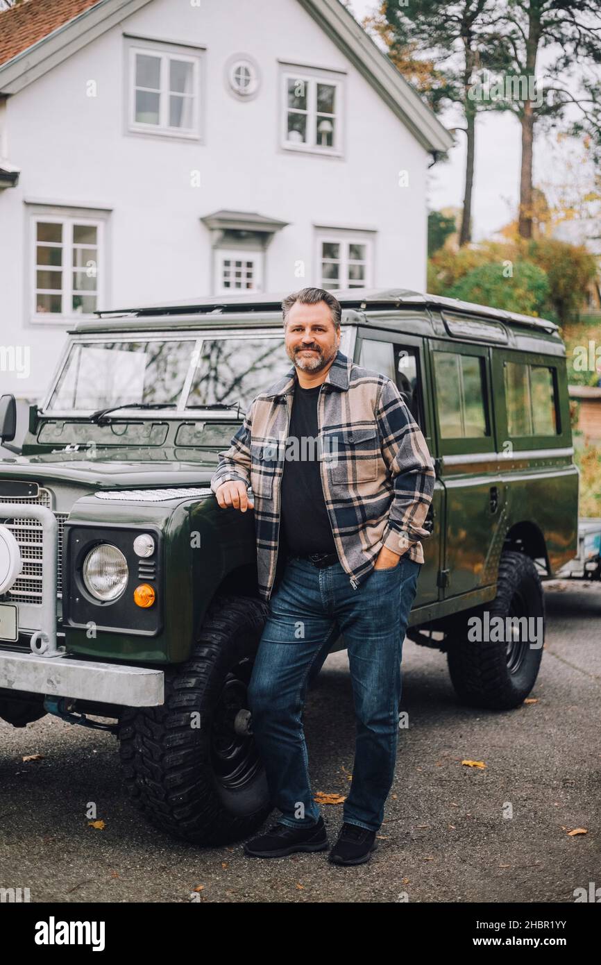 Reifer Mann mit der Hand in der Tasche, der beim Sport-Utility-Vehicle steht Stockfoto