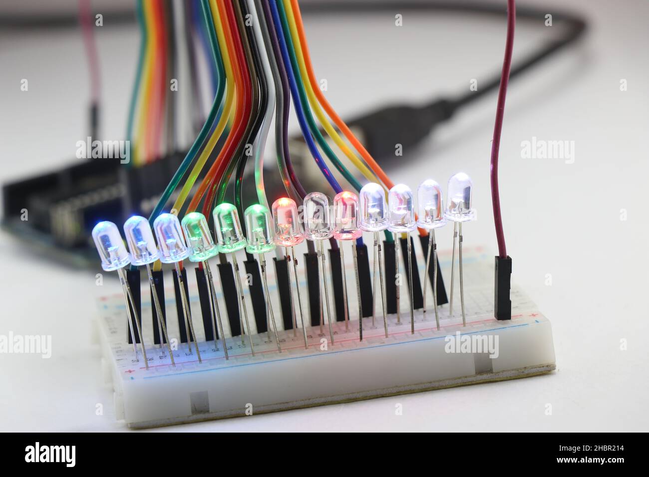 LED-Leuchten, die mehrere Farben emittieren, sind in einer Parallelschaltung auf einer Breadboard-Platine angeschlossen, die von einem Mikrocontroller gesteuert wird und über Überbrückungskabel verbunden ist Stockfoto