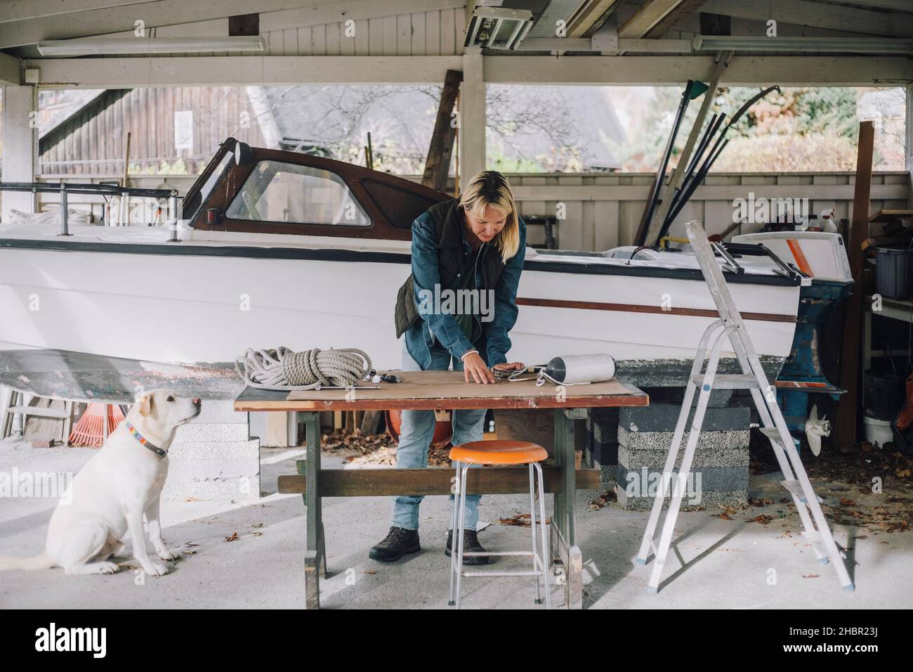 Reife Frau mit Hund Reparatur nautischen Schiff in der Garage Stockfoto