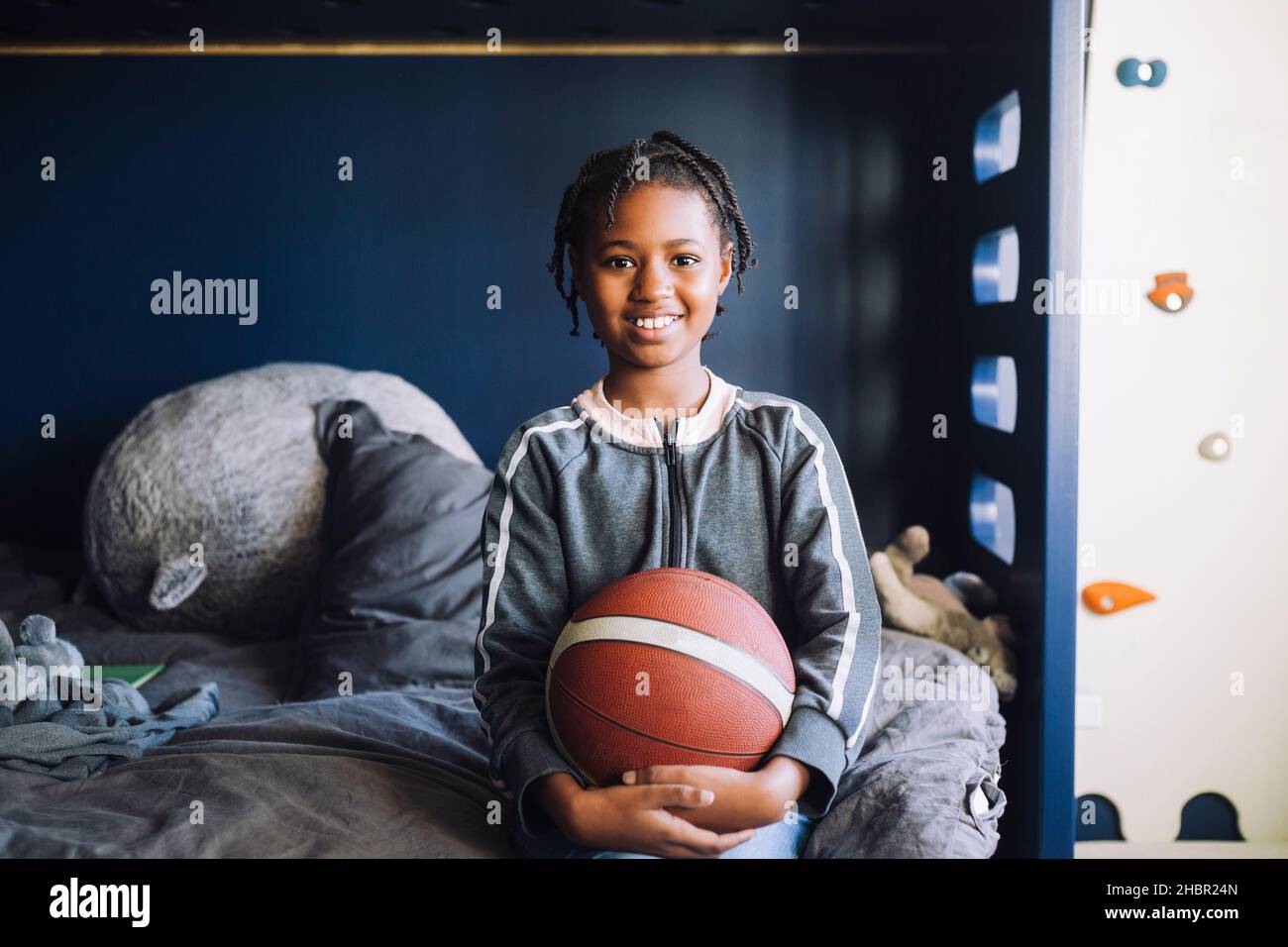 Porträt eines lächelnden Mädchen mit Basketball im Schlafzimmer sitzen Stockfoto