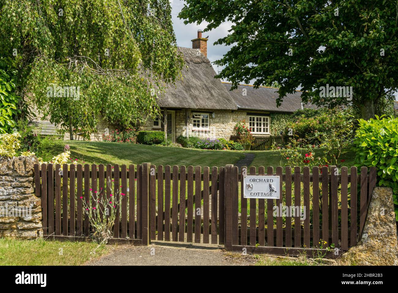 Orchard Cottage, ein freistehendes Steinhaus mit Reetdach, eingerahmt von Bäumen, im Dorf Alderton, Northamptonshire, Großbritannien Stockfoto