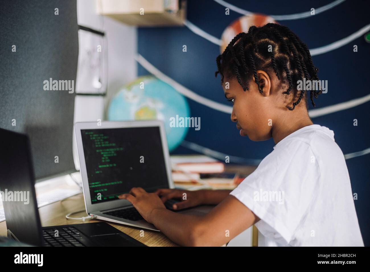 Studentin, die am Tisch Codierung auf dem Laptop lernt Stockfoto