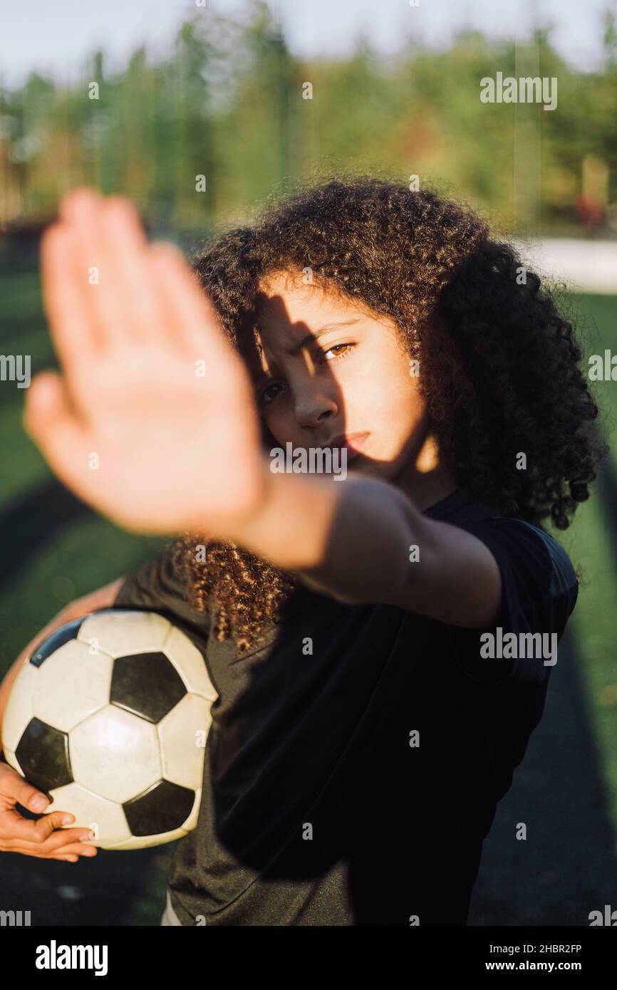 Mädchen, das die Augen vor Sonnenlicht auf dem Sportplatz schützt Stockfoto