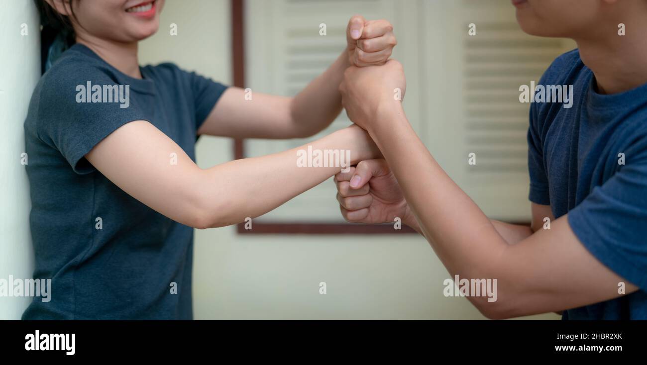 Glückliches junges erwachsenes Paar, das ihre Faust übereinander legt und lächelt. Frohe Ehe. Aufbau von Familienteams. Krankenversicherung für Paare. Stockfoto