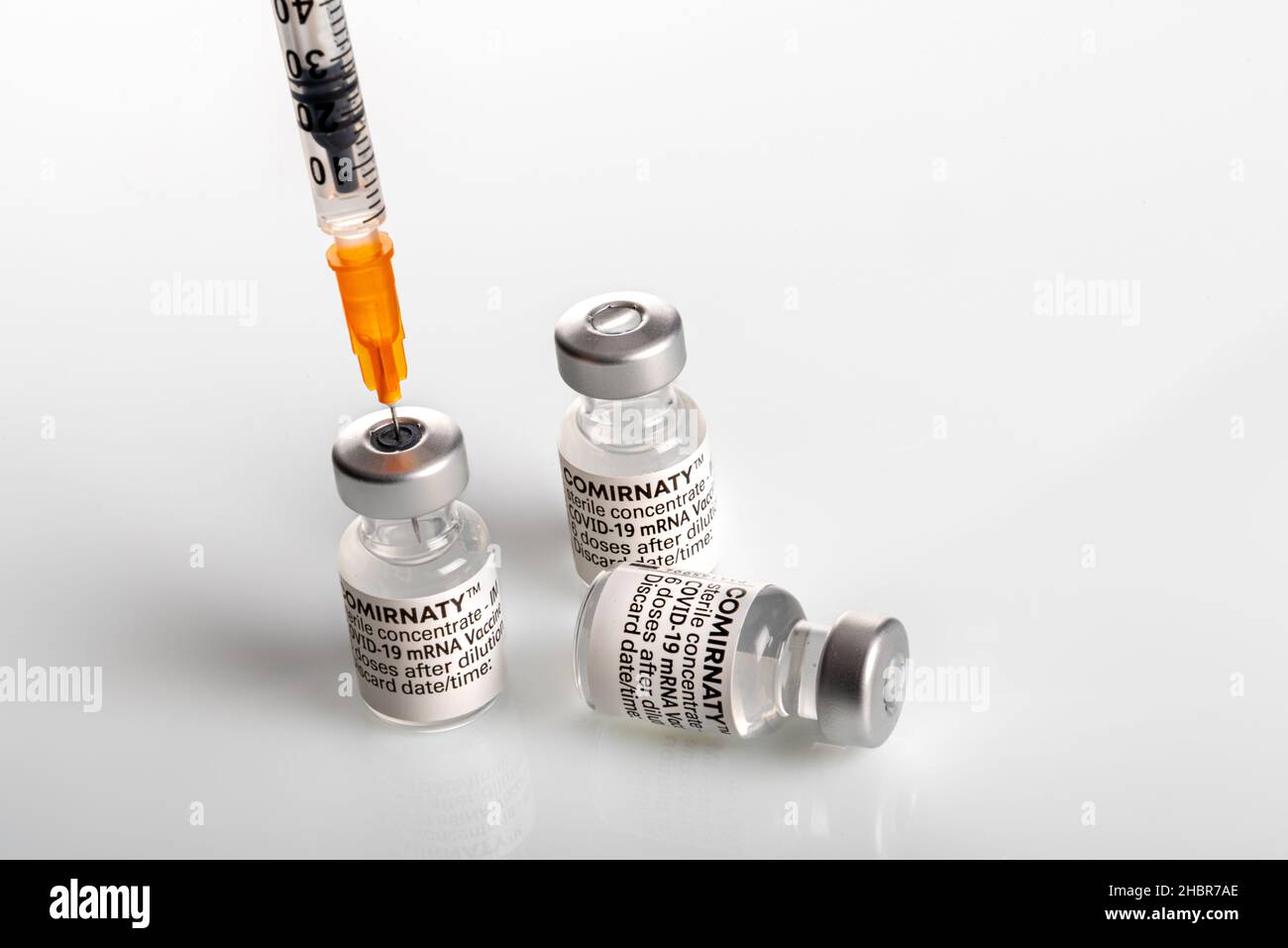 Turin, Italien - 18. Dezember 2021: Pfizer-BioNTech COVID-19-Impfstoff Comirnaty-Fläschchen, drei Fläschchen mit Spritze, die Impfstoffdosis ansaugt, dritte Dosis Conce Stockfoto